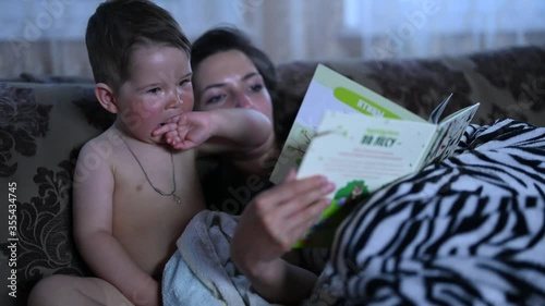 Mom with a child read a book on the couch before going to bed