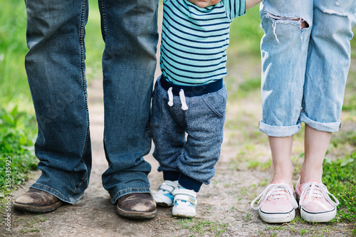 The legs of dad's mom and little son. A family walk in nature. 