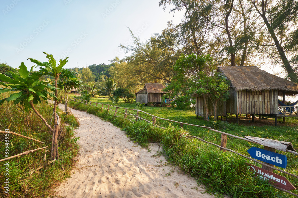 Wooden bungalows and a sandy pathway with a sign at the Koh Rong Sanloem island near Sihanoukville