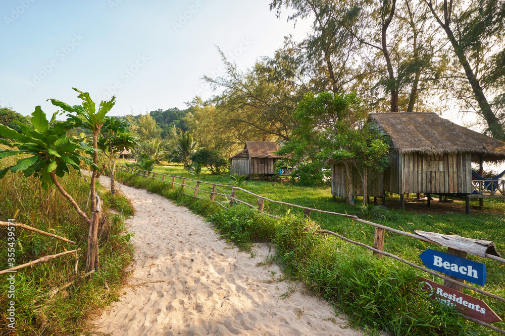 Wooden bungalows and a sandy pathway with a sign at the Koh Rong Sanloem island near Sihanoukville Wooden bungalows and a sandy pathway with a sign at the Koh Rong Sanloem island near Sihanoukville