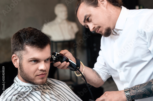 Men's hairstyling and haircutting in a barber shop or hair salon. © zazarock1