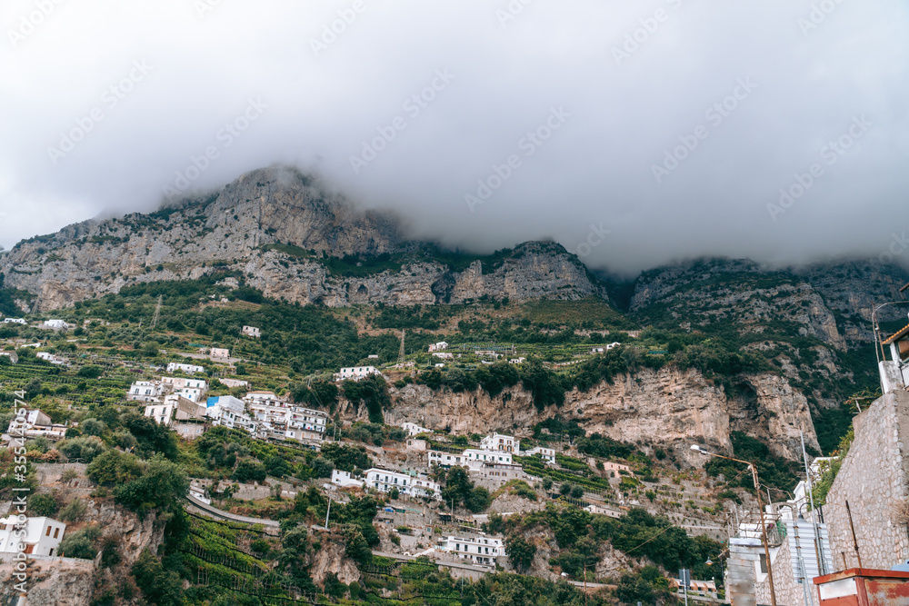 view of the village high in the mountains. Thick gray clouds cover the top. Highland Housing Concept. Olive plantations, houses and hotels. Italian coast Castello Lauritano in Agerola San Lazzaro