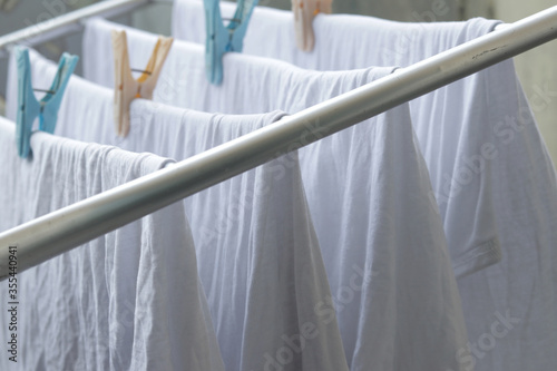 White clothes drying on standing clotheshores with clothespins white inner wear on Rack dryer Collapsible clothes horse with clothes plastic clothespins photo