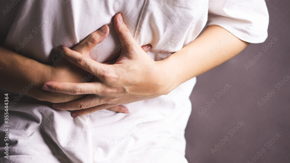 Man suffering from stomachache on grey background.