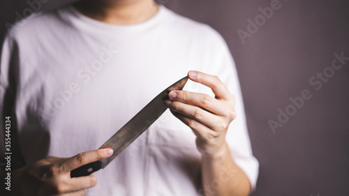 Man holding kitchen knife on gray background.