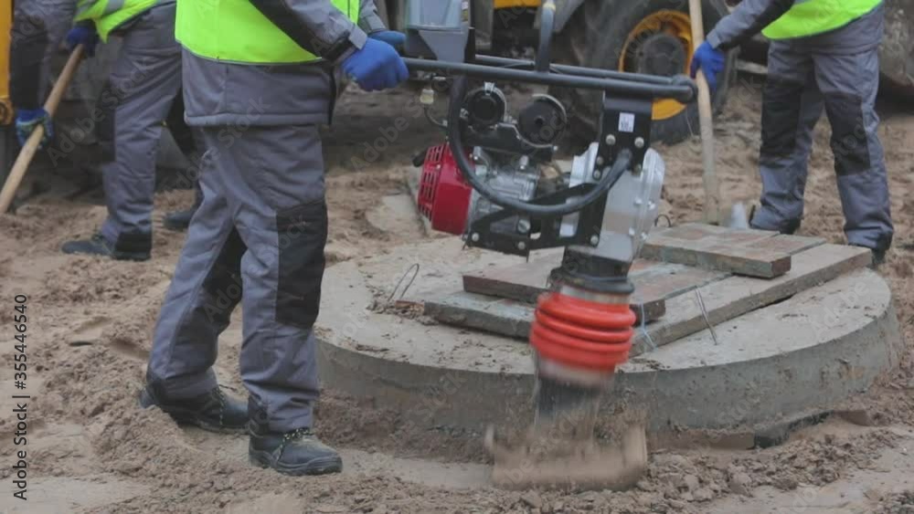 Workers at a construction site, tamping rammer, worker with tamping
