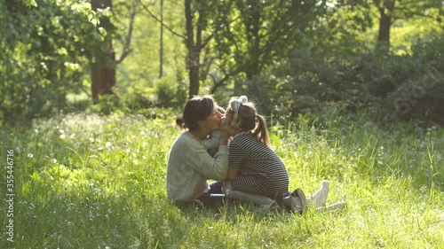 Mother funny play with her daughters elder sister and baby toddler happy family in green park nature