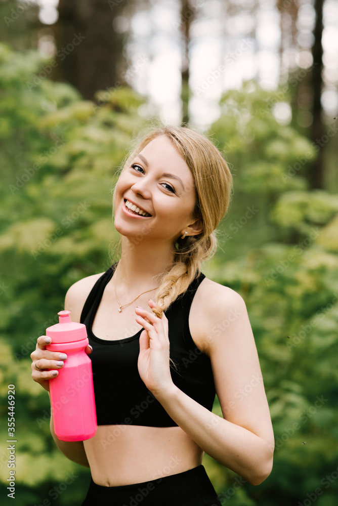Beautiful young girl in sports uniform with a bottle of water doing yoga and sports in the forest in the open air Beautiful young girl in sports uniform with a bottle of water doing yoga and sports in the forest in the open air