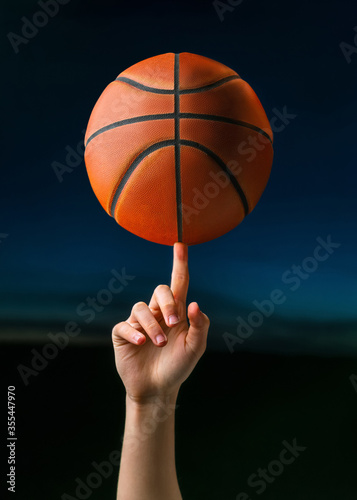 Close up of professional basketball player spinning a ball on hand finger. Street basketball athlete training for competition © CrispyMedia