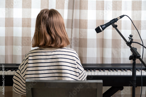 Closeup of teenager playing piano in home music studio. Girl having online class and practicing on modern electric piano