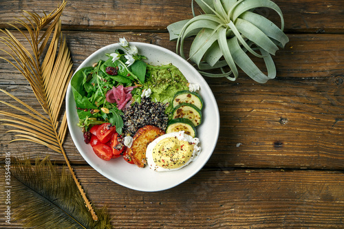 Superfood - a bowl of quinoa, fried cheese, guacamole, poached poached egg and cherry tomatoes on a wooden background