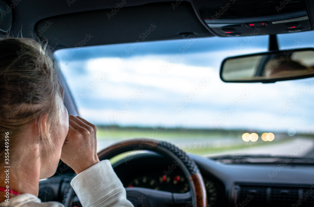 A tired woman driver yawns behind the wheel