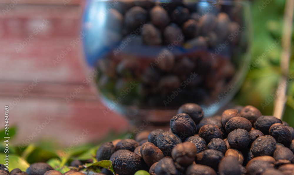 Green and roasted coffee beans (Coffea sp) in glass bowl on wooden rustic background