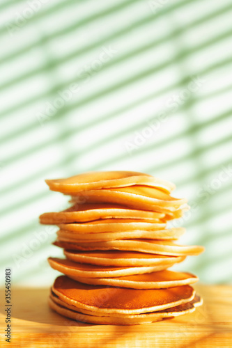 Stack of tasty pancakes on wooden dish and shadow background. Hard light. Soft selective focus. Home cooking concept. photo