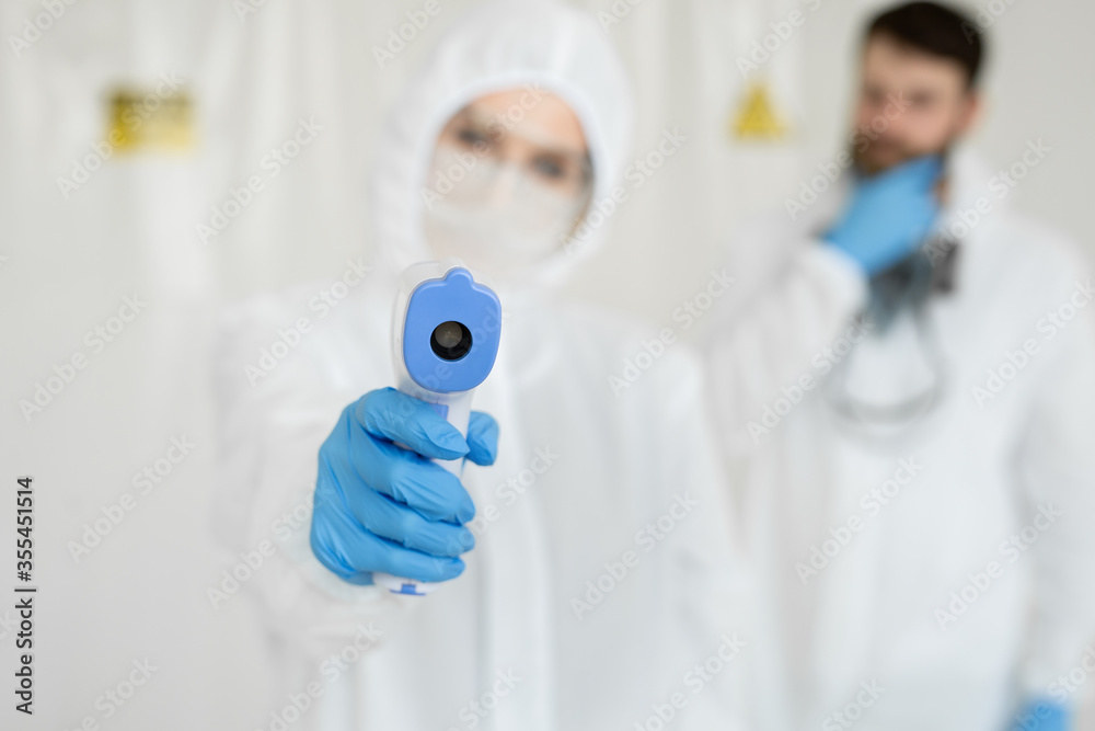 Medical professionals in protective clothing measuring contactless fever at Covid-19 test center during coronavirus epidemic Medical professionals in protective clothing measuring contactless fever at Covid-19 test center during coronavirus epidemic