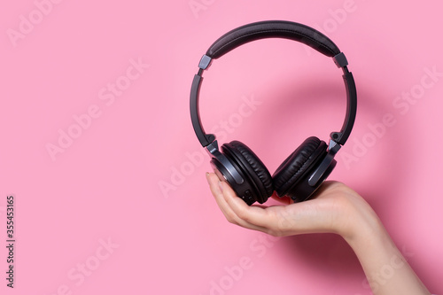 earphone on a pink background. Women's headphones. Place for signature.headphones in the hands of a girl