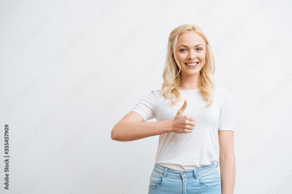 happy attractive girl showing thumb up while smiling at camera isolated on white happy attractive girl showing thumb up while smiling at camera isolated on white