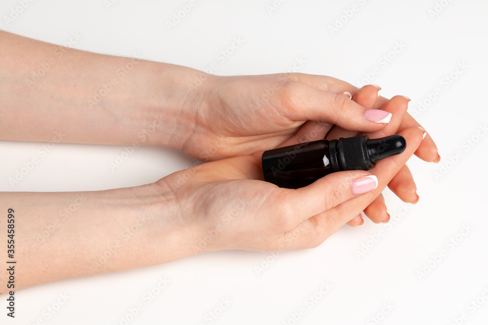 Female hand holding cosmetic bottle on white Female hand holding cosmetic bottle on white
