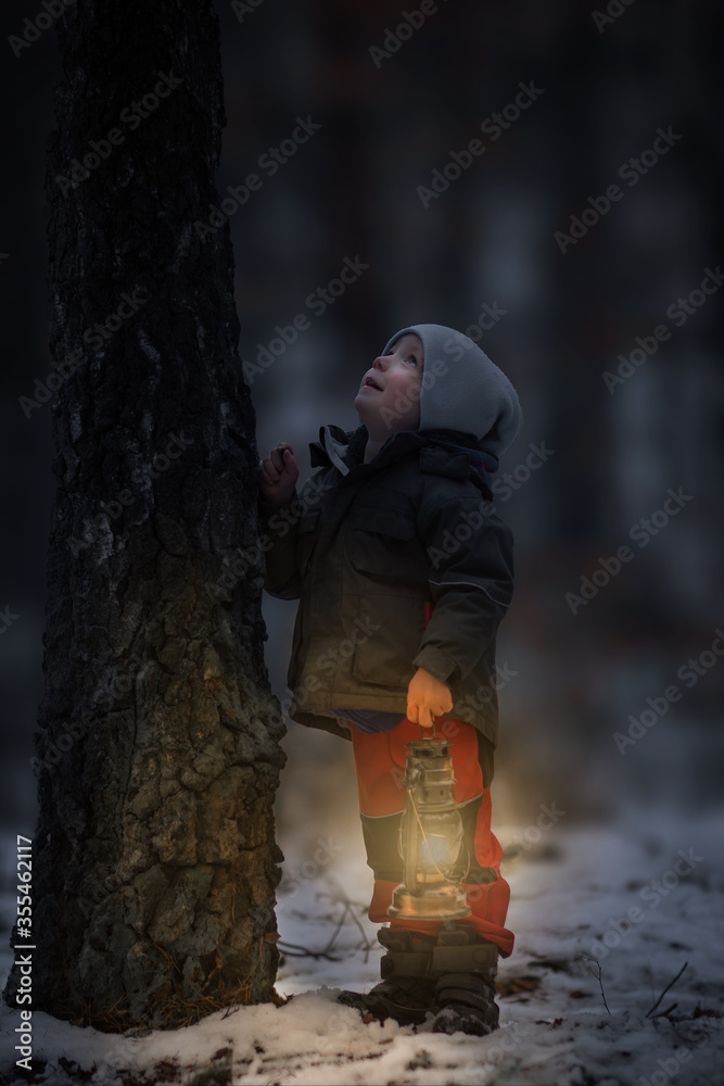 Little boy in the forest with lantern, boy in dark with light look like dwarf Little boy in the forest with lantern, boy in dark with light look like dwarf