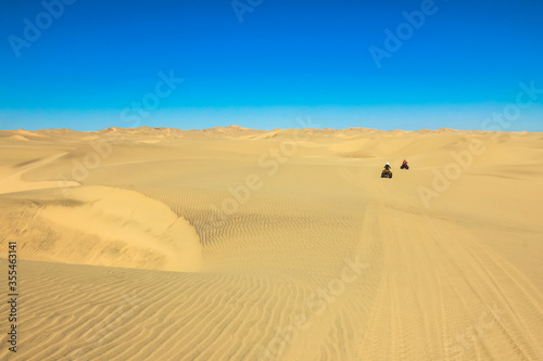Quad driving people - two happy bikers in sand desert dunes  Africa  Namibia  Namib  Walvis Bay  Swakopmund.
