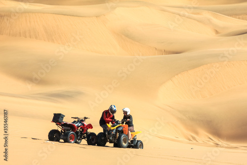 Quadbike driving people having breakdown and stuck in sand.