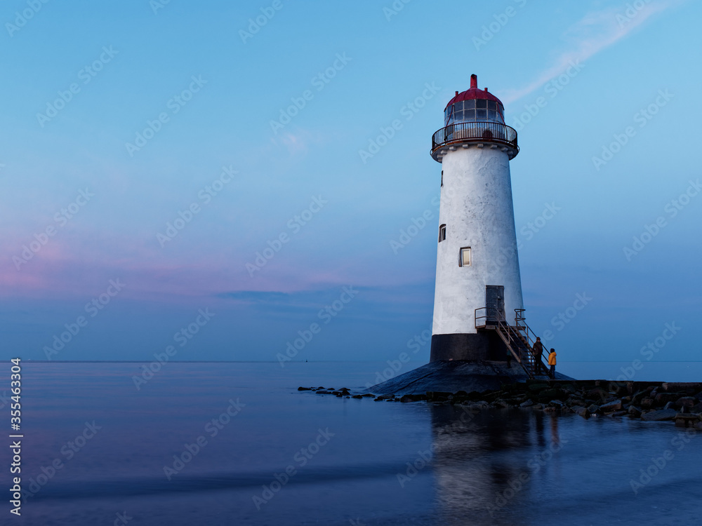 The Point of Ayr Lighthouse on a very quiet beach at Talacre, North Wales against a blue and purple sky at sunset on new years day
