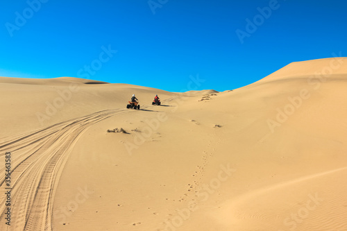 Quad driving people - two happy bikers in sand desert dunes  Africa  Namibia  Namib  Walvis Bay  Swakopmund.