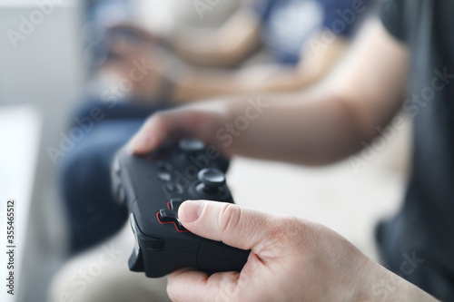 Two male friends play video games against home background. Gaming console concept