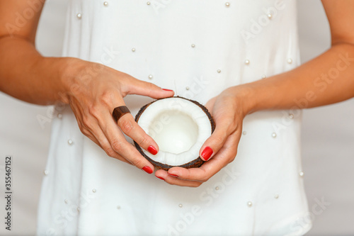 Hands of a young woman holding half a coconut. healthy eating concept