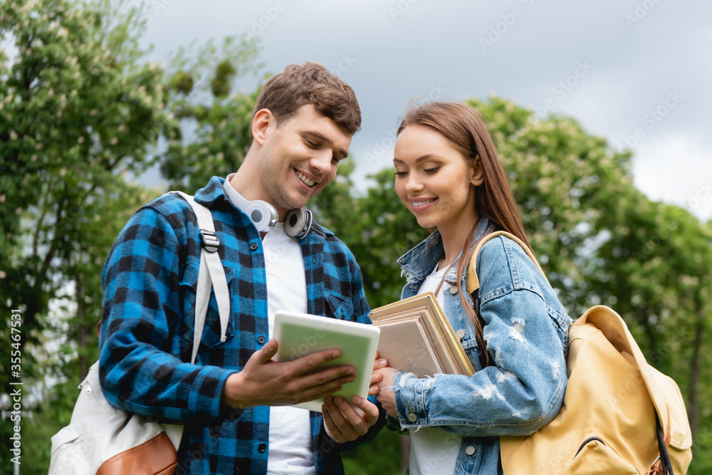 cheerful students with backpacks and books looking at digital tablet cheerful students with backpacks and books looking at digital tablet