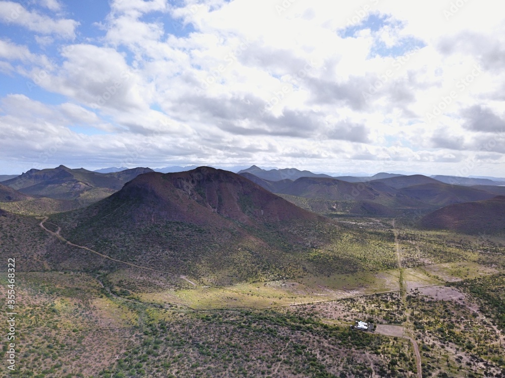 drone view of desert area with mountains trails, blu sky and white clouds