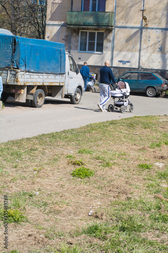 A man walks with a stroller near the house.