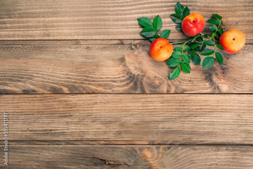 Rustic wooden background with apricots and green leaves. Concept copy space.