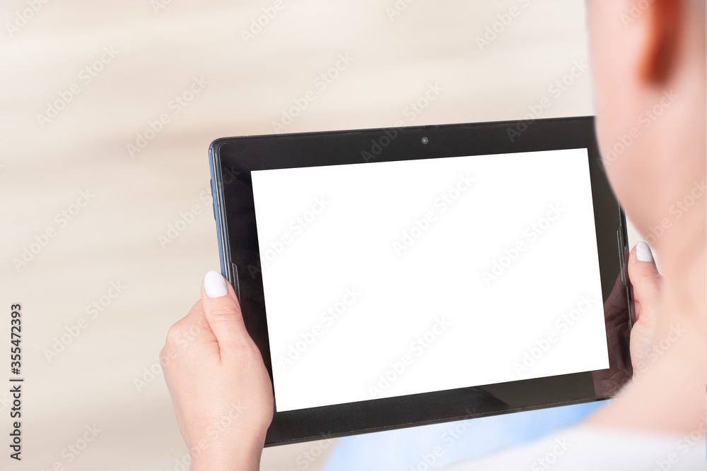 Mockup of a woman sitting and holding black tablet with blank white desktop screen