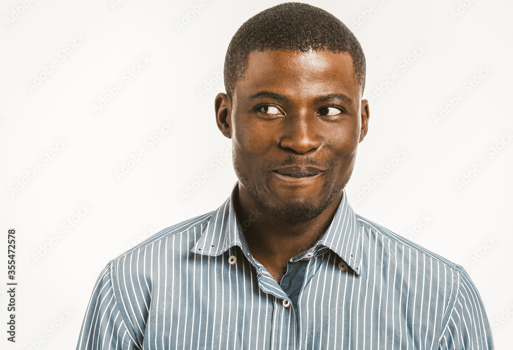Smiling African American man looking at side. Dark-skinned young man in striped shirt isolated on white background. Toned image. Smiling African American man looking at side. Dark-skinned young man in striped shirt isolated on white background. Toned image.