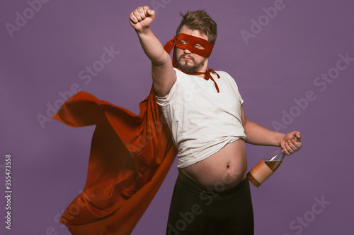 Tablou pe pânză Drunk super antihero holding wine bottle showing his tummy