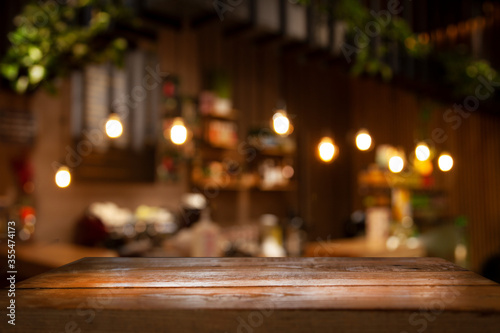 Foto Empty wooden table top on blur light golden bokeh of cafe restaurant, bar in a dark background