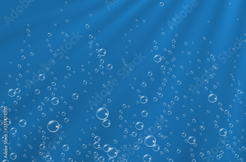 Underwater background with sunbeams and air bubbles. Texture of water surface.