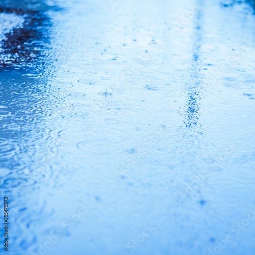 Raindrops and ripples on water surface closeup background