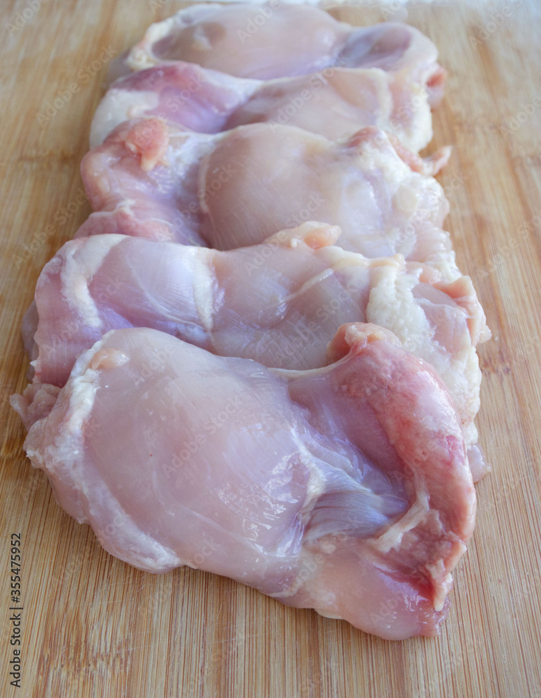 Skinless chicken thigh filet on a wooden surface. Ingredient, fresh meat for cooking. Parts of chicken, protein. Dietary meat of domestic chickens. Thigh fillet on a blackboard Skinless chicken thigh filet on a wooden surface. Ingredient, fresh meat for cooking. Parts of chicken, protein. Dietary meat of domestic chickens. Thigh fillet on a blackboard