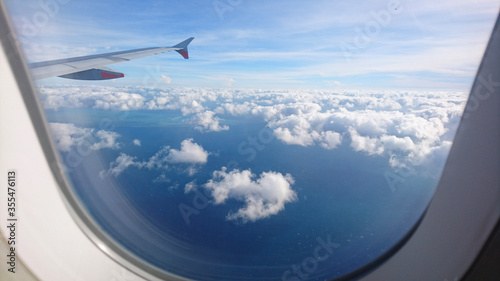 flying and traveling, view from airplane window on the wing on blue sky with some clouds