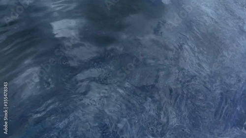 background texture of water near drains from waste from the plant with oil stains and reflection of the sky in the surface
