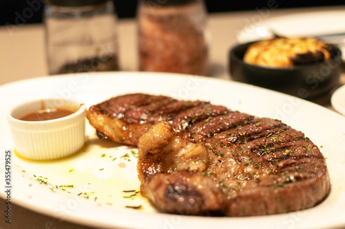 Medium grilled strip loin beef steak with pepper sauce in warm light at restaurant. 