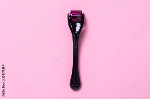 Derma roller on a pink background. The device for cosmetic procedures of mesotherapy. View from above, flat lay, photo