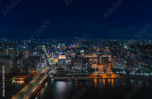 Aerial nocturn panoramic view of the Azumabashi bridge on Sumida river leading to the illuminated buildings and skyscrapers of Asakusa in Tokyo.