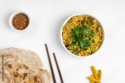 Kichari in a white plate on a light table near condiments and tortillas top view photo