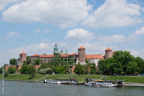 Fototapeta Naklejka Na Ścianę i Meble -  Wawel Royal Castle in Krakow, Poland. Exterior view from the Vistula River. Barges with restaurants standing by the river bank.