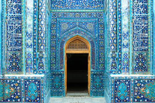 Decorative muslim mosaic tiles at the arched entrance with open door of Shah-I-Zinda in Samarkand, Uzbekistan