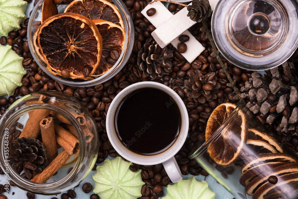 A white Cup of coffee on coffee beans, on a light blue wooden table. Wooden table. Fir cones on the table. Green marshmallows and white marshmallows. Dried citrus. Brown background. A white Cup of coffee on coffee beans, on a light blue wooden table. Wooden table. Fir cones on the table. Green marshmallows and white marshmallows. Dried citrus. Brown background.
