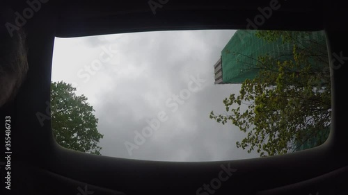 View of the grey cloudy sky through opened sunroof of the moving car. photo